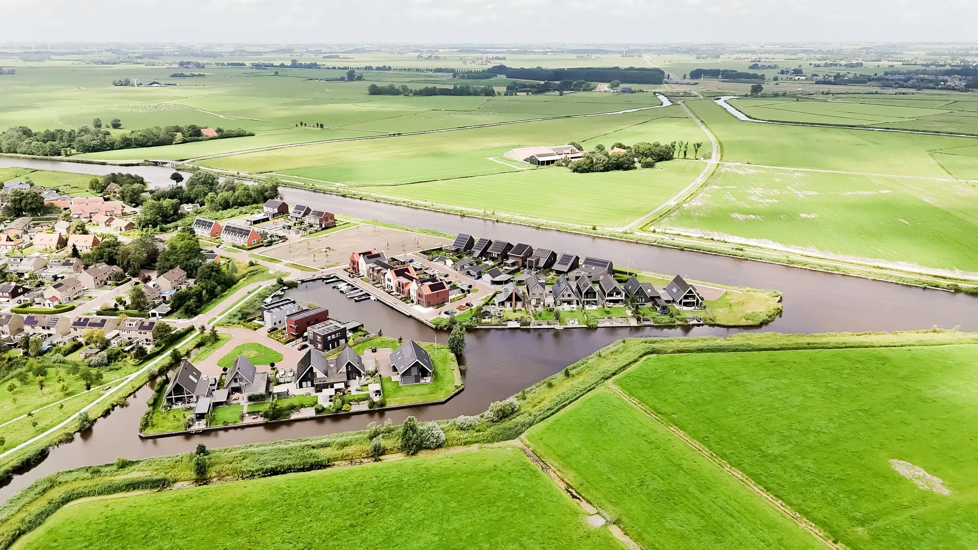 Luchtfoto van een Fries dorp aan het water, omringd door weiland