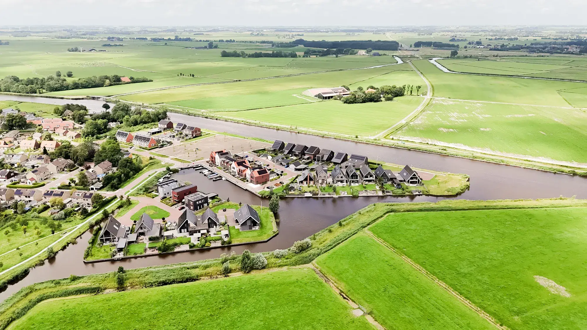 Luchtfoto van een Fries dorp aan het water, omringd door weiland