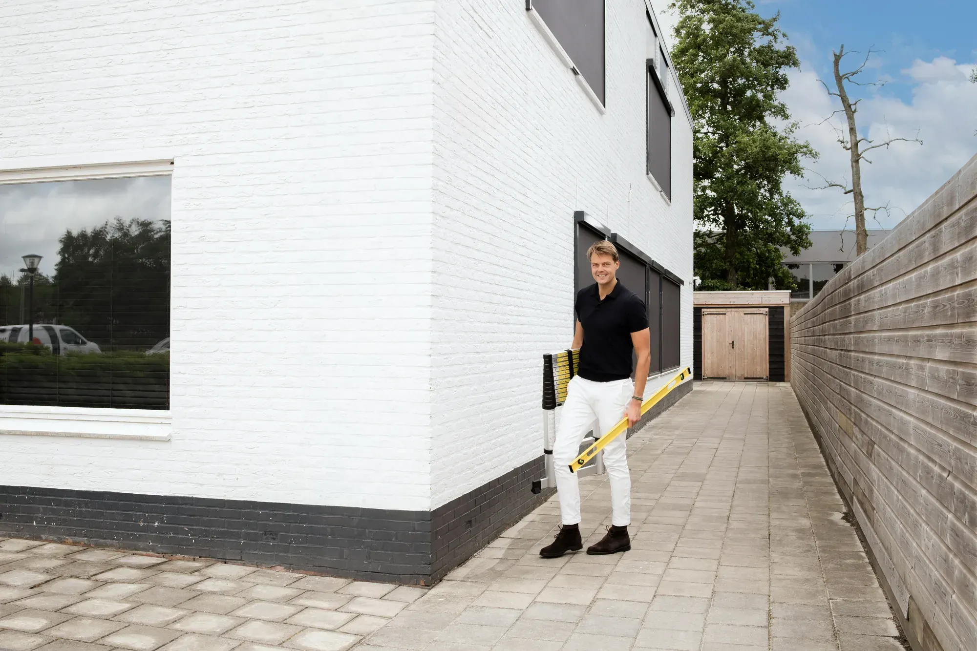 Adviseur van MV Adviseurs met waterpas bij de buitengevel van een woning